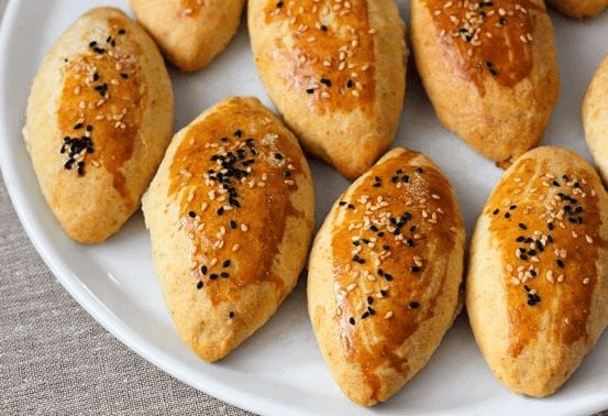 Golden yeasted pastry buns topped with sesame and nigella seeds.
